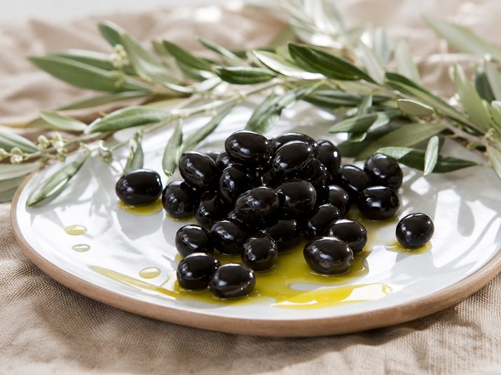 Azeitonas pretas com azeite de oliva em um prato branco.